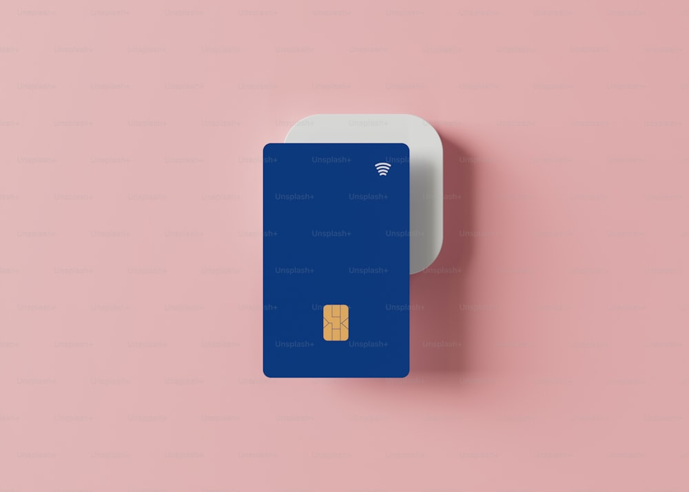una carta di credito blu seduta sopra una superficie rosa