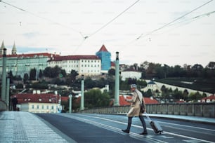 Un uomo d'affari maturo con smartphone e valigia che attraversa una strada nella città di Praga, messaggi di testo.