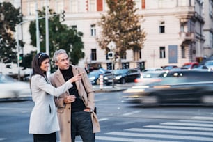 Homem alegre e mulher parceiros de negócios atravessando a estrada ao ar livre na cidade de Praga, conversando. Espaço de cópia.