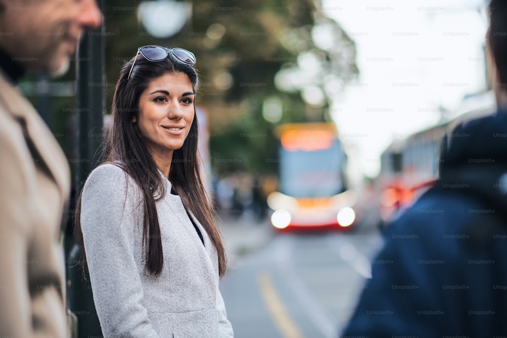 Attractive woman standing outdoors in city, waiting for a tram. Copy space.