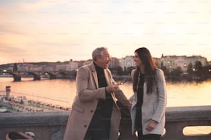 Cheerful man and woman business partners standing by a river in city of Prague at dusk, expressing excitement.