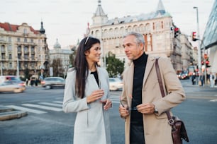 Ein reifer Mann und eine junge Geschäftspartnerin stehen im Freien in der Stadt Prag und unterhalten sich.