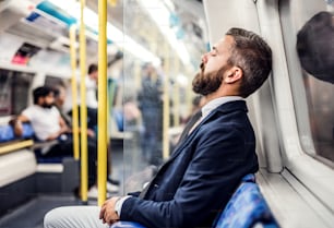 市内の地下鉄の中で疲れた眠りにつく流行に敏感なビジネスマン、仕事に旅行する。