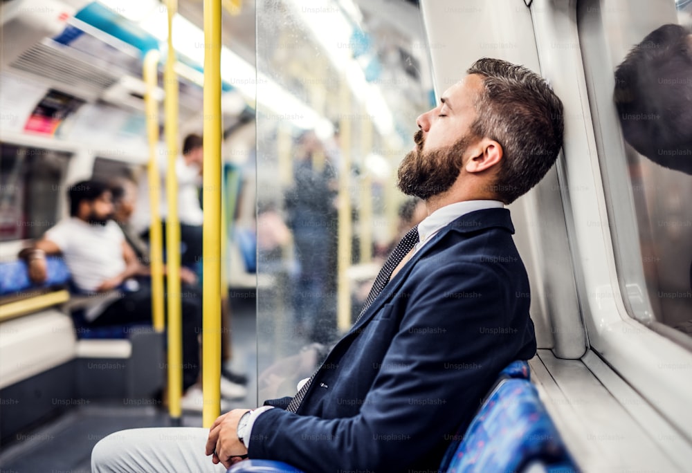 Müde schlafender Hipster-Geschäftsmann in der U-Bahn in der Stadt, auf dem Weg zur Arbeit.