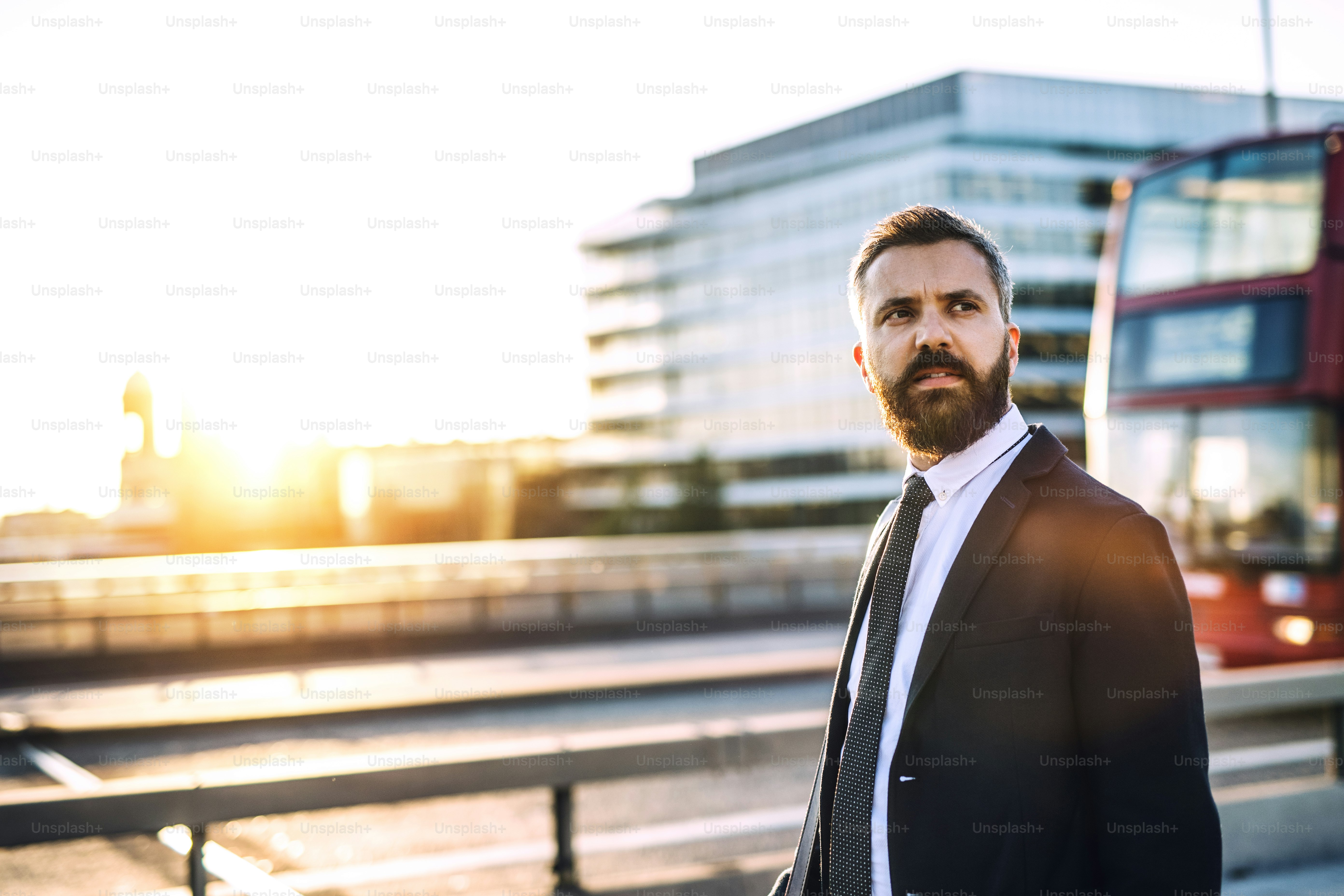 Hombre de negocios hipster con chaqueta y corbata caminando por la carretera en Londres al atardecer. Espacio de copia.