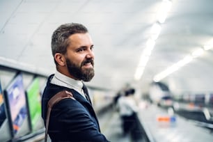 Happy hipster businessman using escalator in subway, travelling to work.