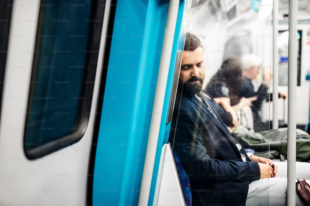 피곤한 잠자는 힙스터 사업가가 도시의 지하철 안에서 일하러 간다.