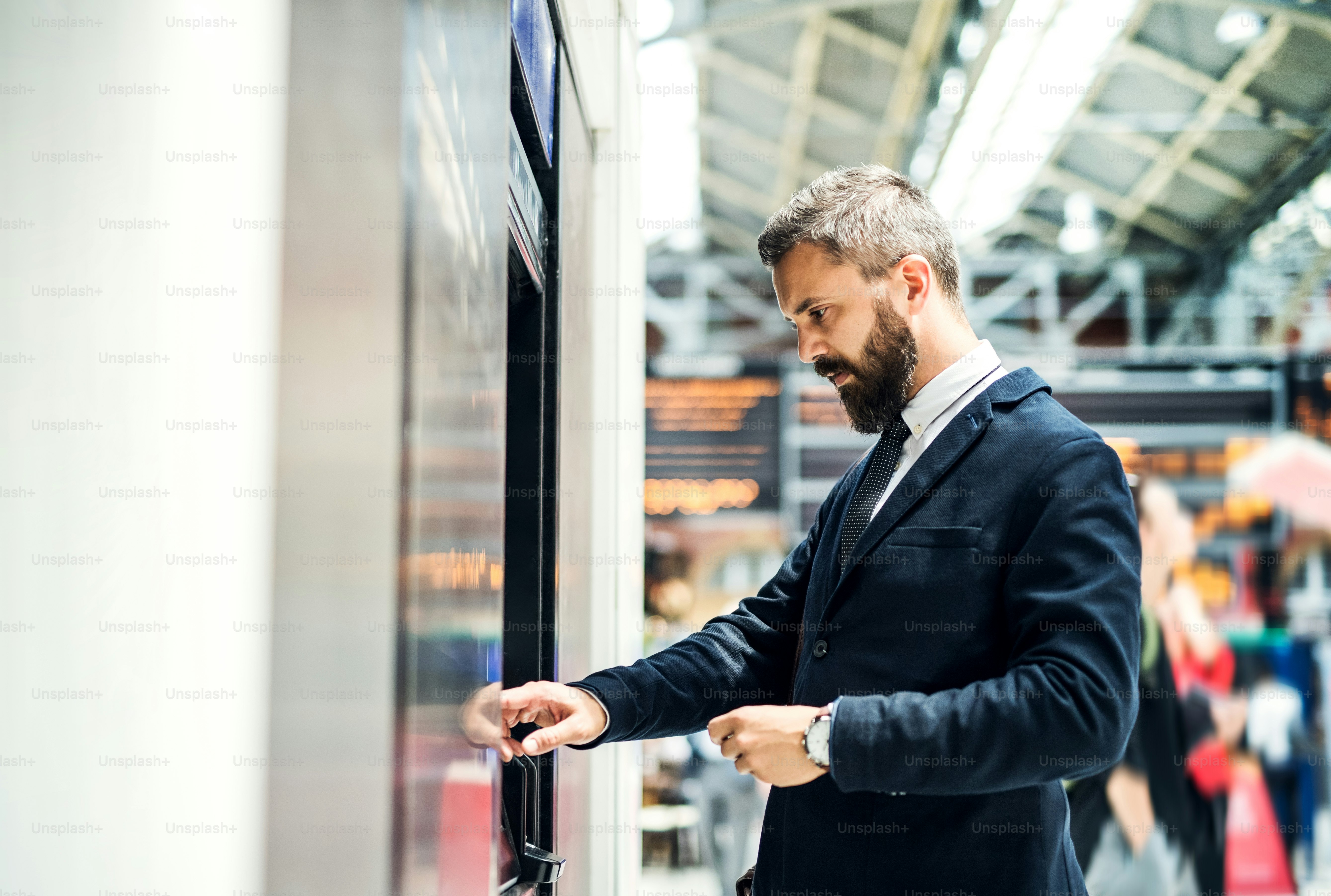 Hipster businessman buying a ticket in a machine inside subway station. Copy space.
