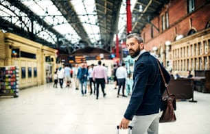 Hombre de negocios hipster con maleta caminando dentro de la estación de metro en Londres. Espacio de copia.