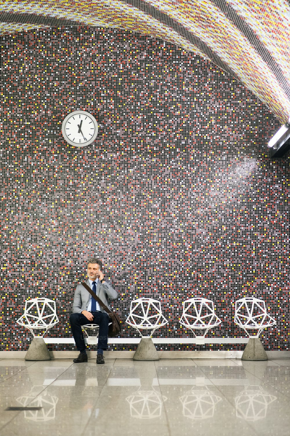 Belo empresário maduro em uma cidade. Homem com smartphone esperando o trem na estação de metrô, fazendo um telefonema.