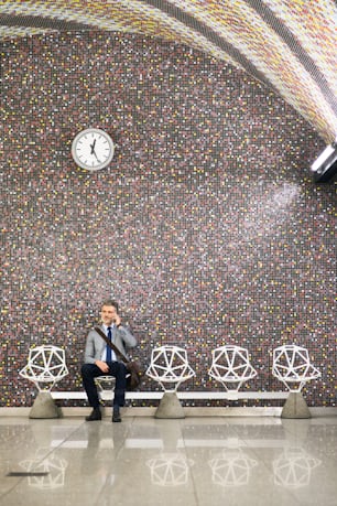 Handsome mature businessman in a city. Man with smartphone waiting for the train at metro station, making a phone call.