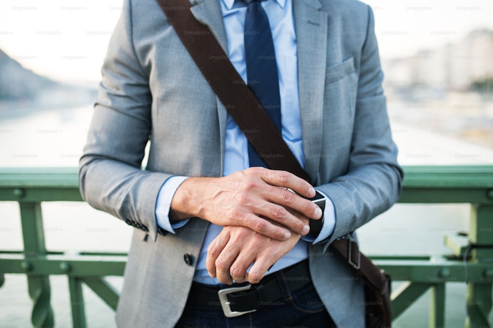 Unrecognizable businessman with smartwatch in a city, checking the time.
