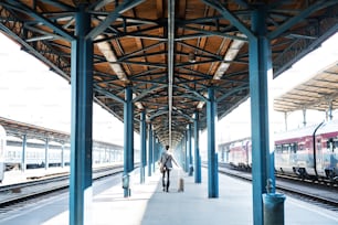 Belo empresário maduro em uma cidade. Homem andando na plataforma ferroviária na estação de trem. Vista traseira.