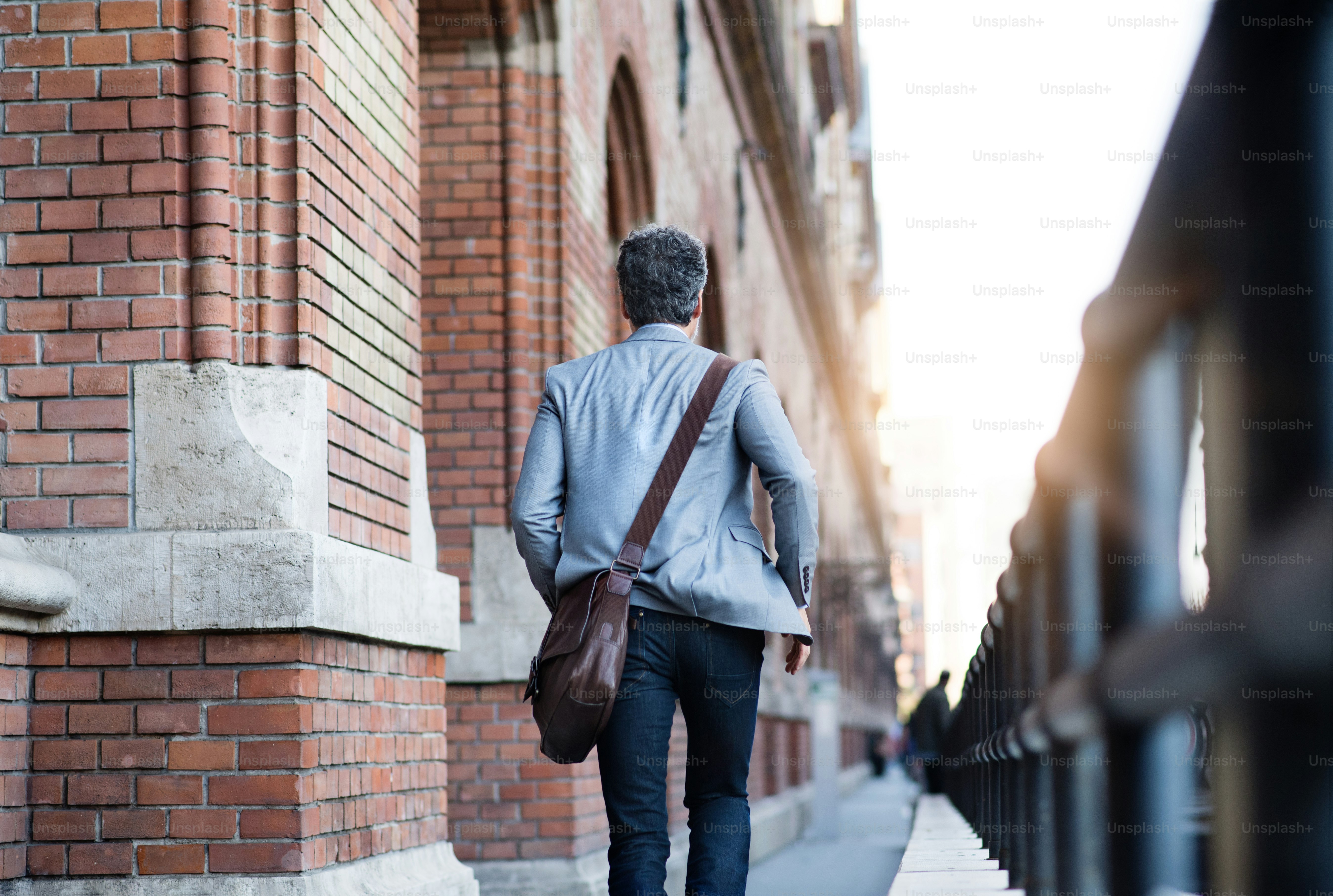 Handsome mature businessman walking in a city. Rear view
