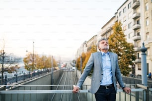 Handsome mature businessman in a city., taking a moment to relax