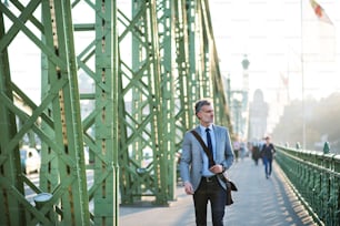 Handsome mature businessman in a city, walking on the bridge.