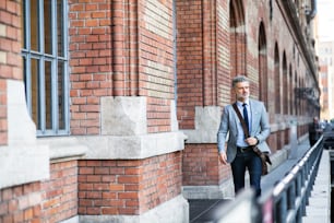 Handsome mature businessman walking in a city.