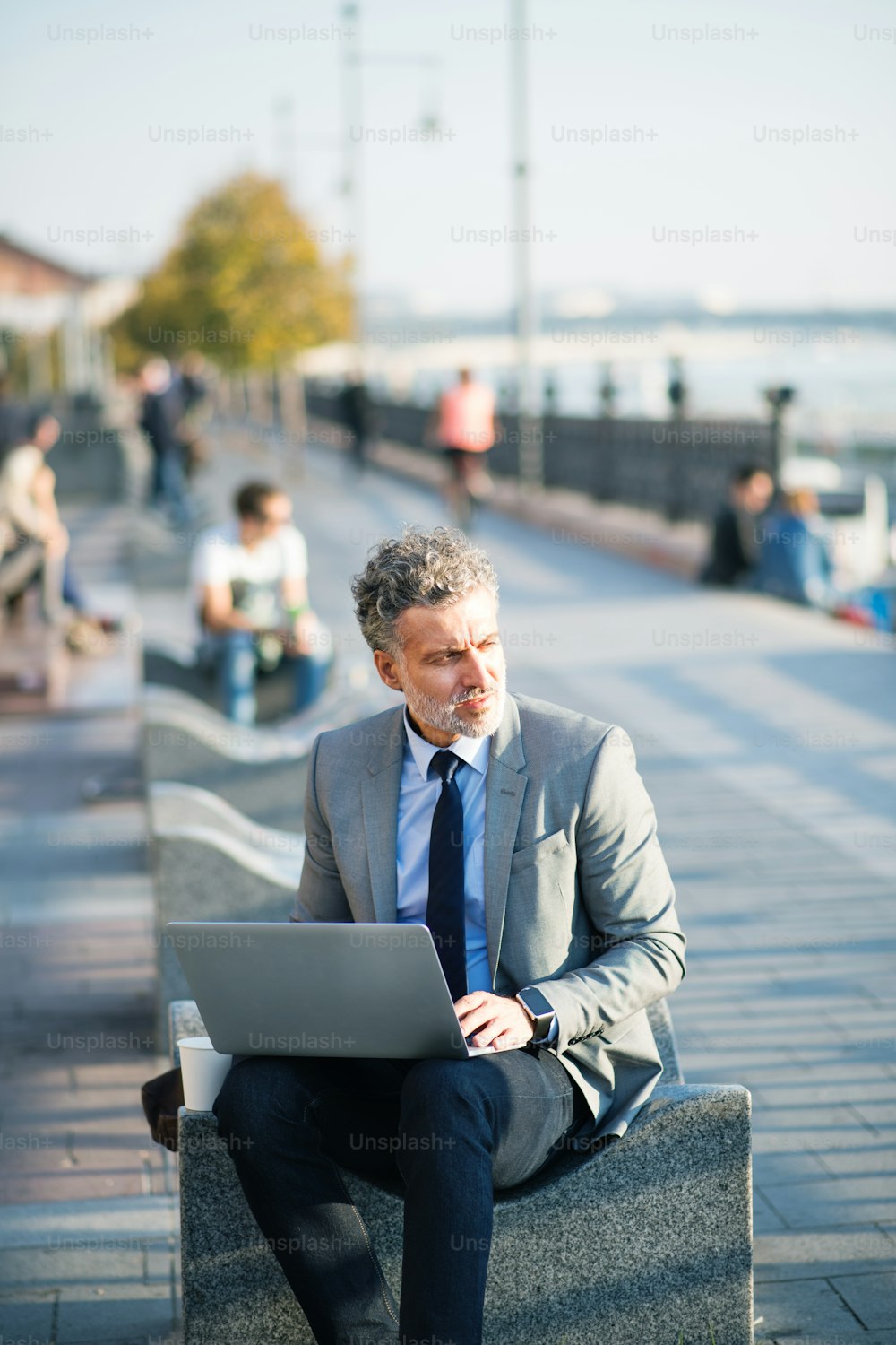 Handsome mature businessman with laptop in a city.