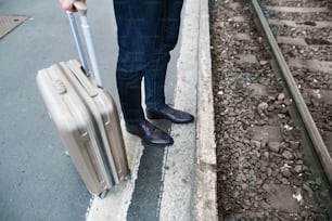 Legs of unrecognizable businessman in a city. Man waiting for the train at the railway station.
