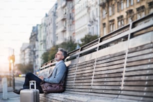 Belo empresário maduro em uma cidade, sentado em um banco, esperando.