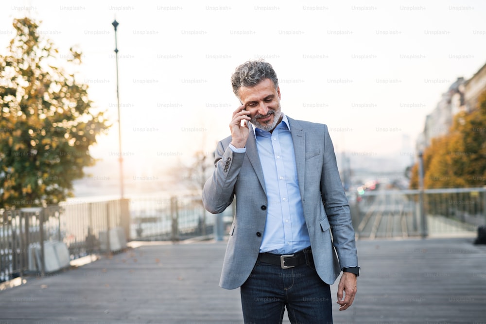 Handsome mature businessman with smartphone in a city. Man making a phone call.
