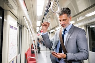 Belo empresário maduro em uma cidade. Homem com smartphone viajando de trem de metrô.
