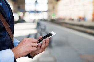 Empresário maduro irreconhecível com um smartphone em uma cidade, enviando mensagens de texto.