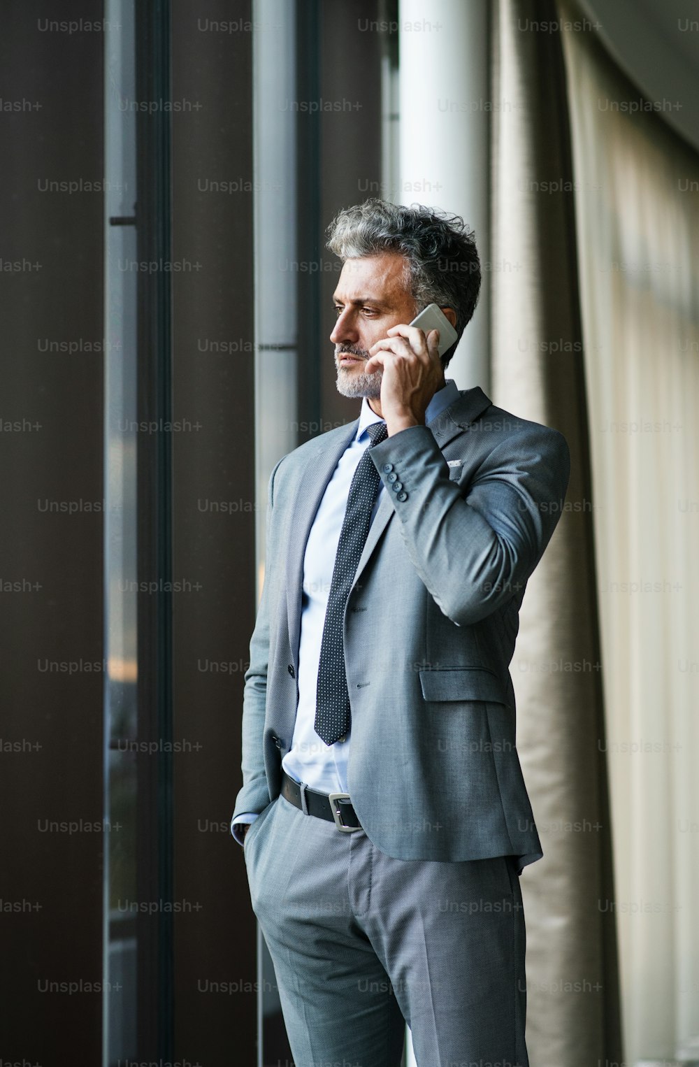 Reifer Geschäftsmann in einem Hotel mit einem Smartphone. Mann, der einen Anruf tätigt. Reifer Geschäftsmann in einem Hotel mit einem Smartphone. Ein Mann telefoniert, geht spazieren.