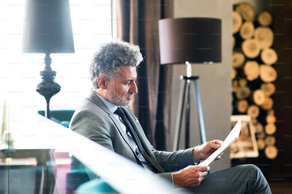 Mature businessman reading in a hotel lounge. Man sitting in a bar or a cafe.