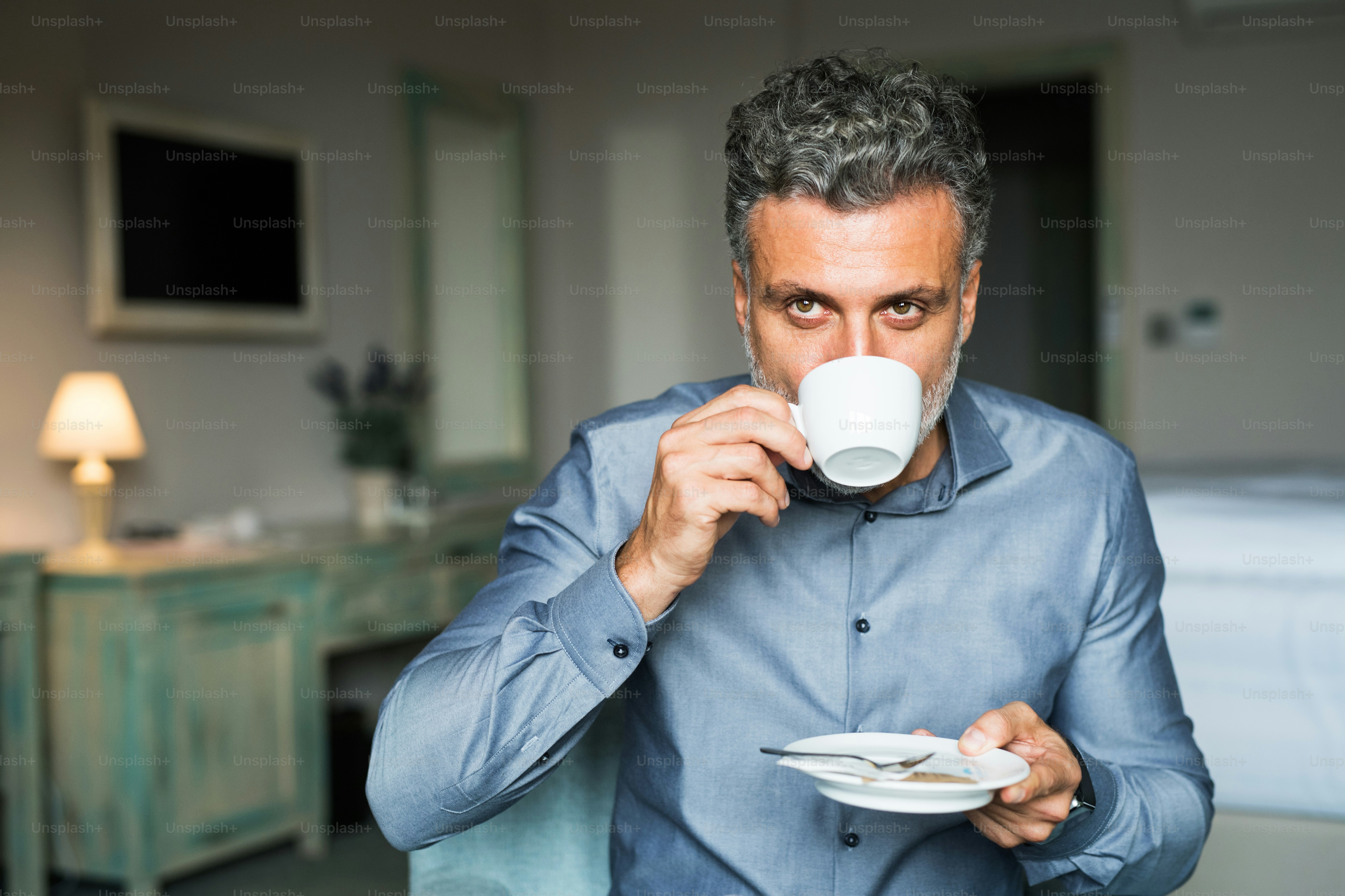 Maturo, bell'uomo d'affari che beve caffè in una stanza d'albergo