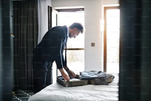 Handsome mature businessman taking his jacket off in a hotel room.