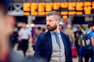 Hipster businessman in suit waiting at the crowded London train station