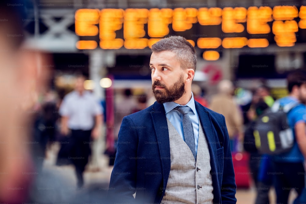 Hombre de negocios hipster en traje esperando en la concurrida estación de tren de Londres