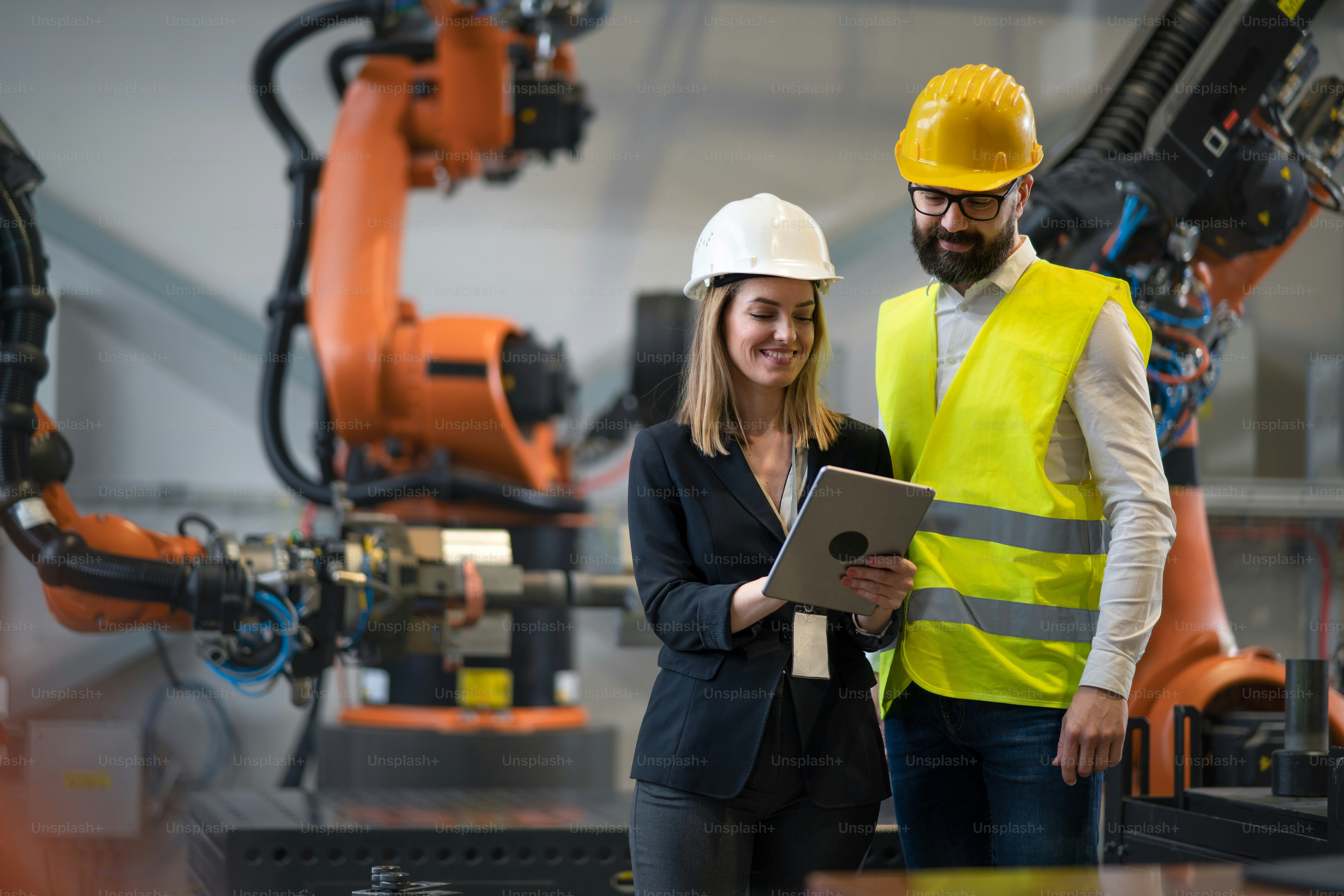 Engineers planning production optimization with robot arms in a factory