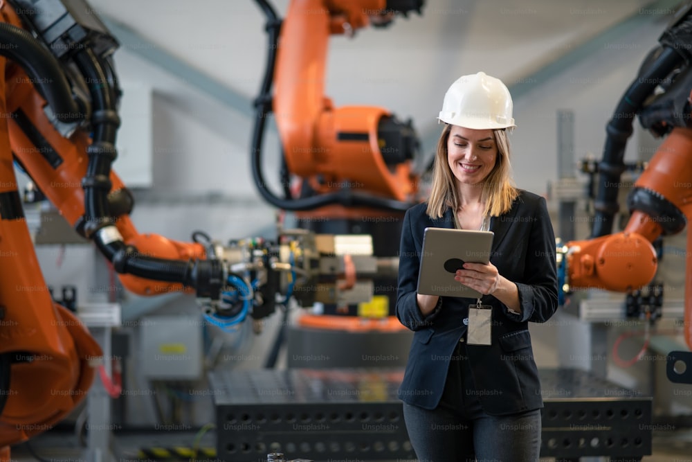 A female chief engineer in modern industrial factory using tablet and making audit.