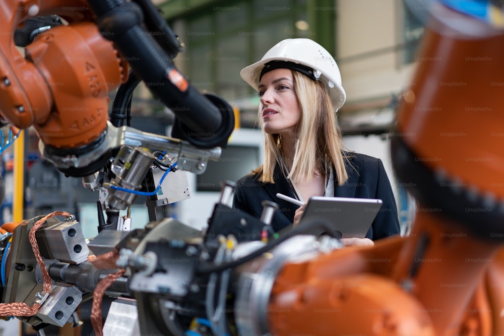 현대 산업 공장의 여성 수석 엔지니어가 태블릿을 사용하고 감사를 하고 있습니다. 긴 각도 보기.
