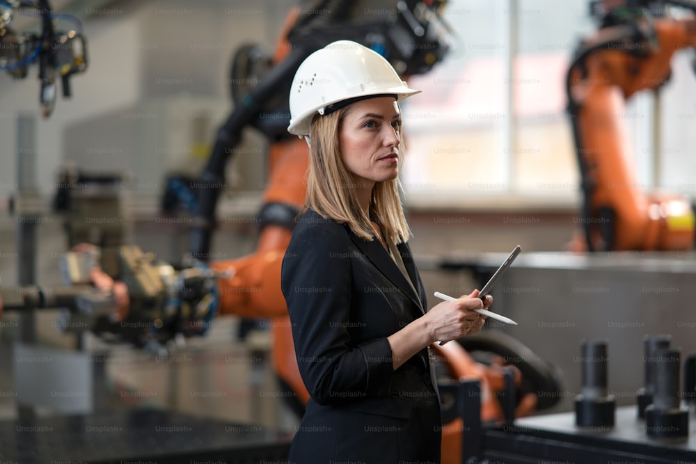 A portrait of female chief engineer in modern industrial factory using tablet.