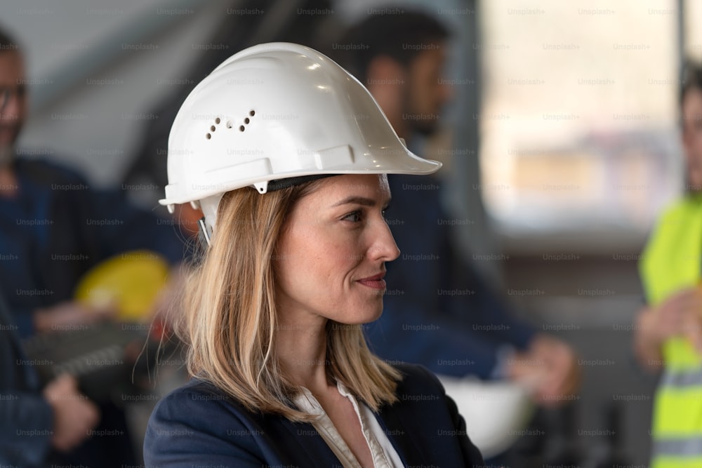 Side view of female chief engineer in modern industrial factory looking at camera.