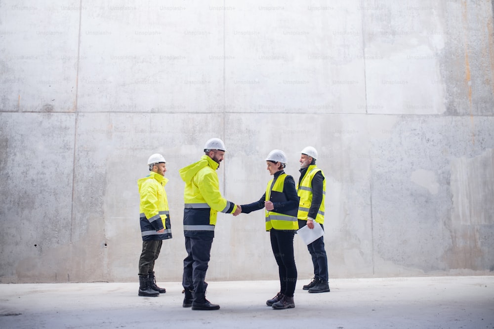 A group of engineers standing on construction site, shaking hands. Copy space.