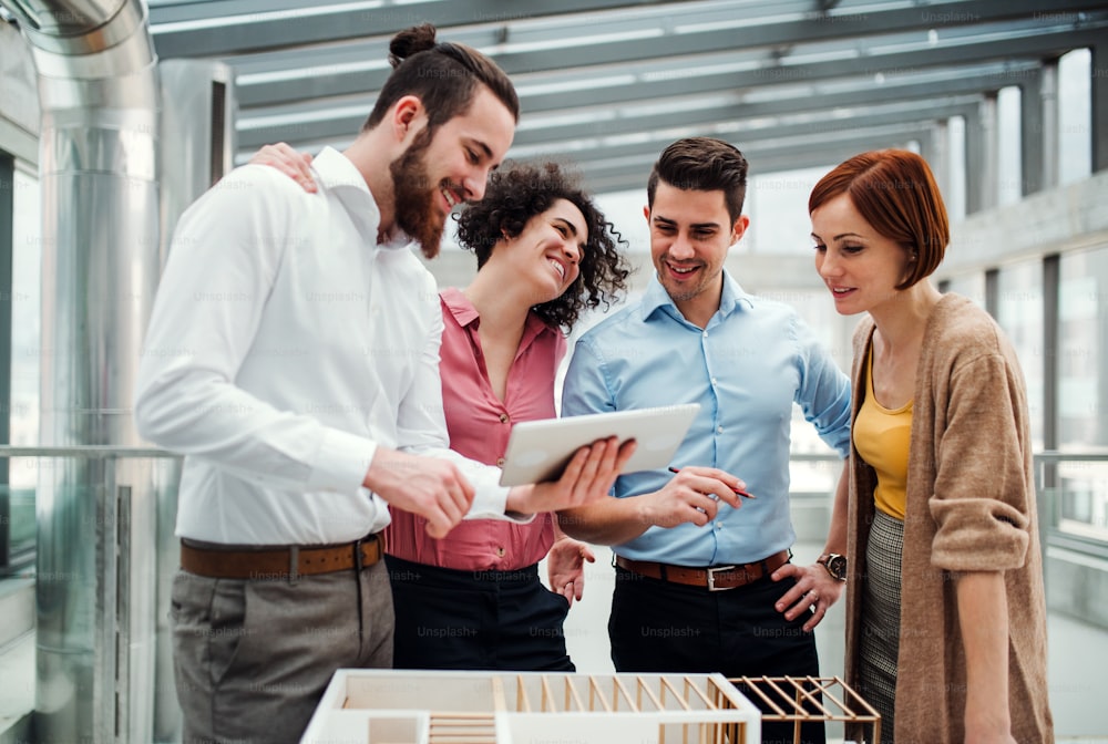 A group of young businesspeople standing near a staircase, talking.