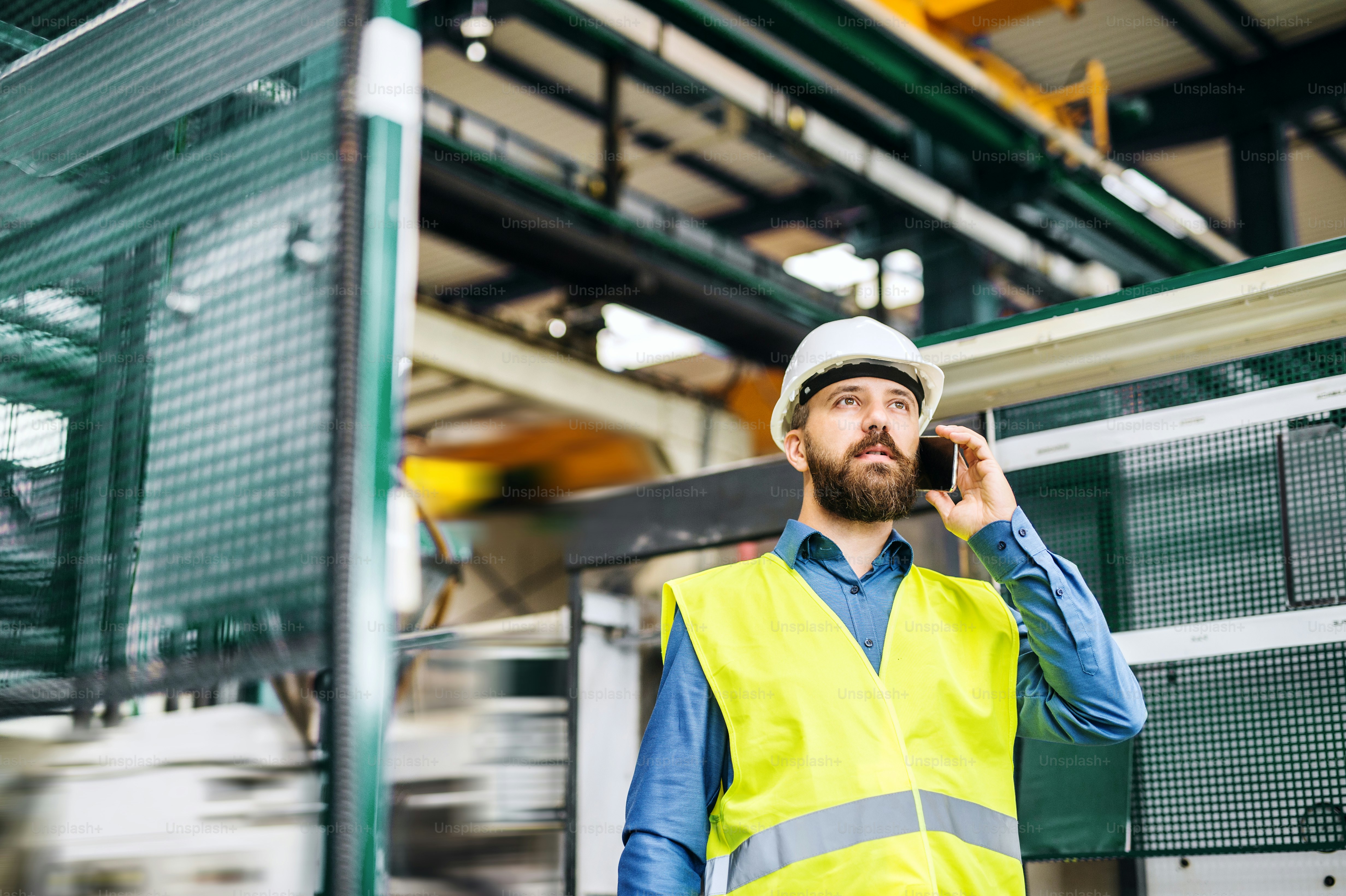 A portrait of a mature industrial man engineer with smartphone working ...