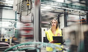 Uma engenheira industrial com fone de ouvido em uma fábrica, trabalhando. Espaço de cópia.