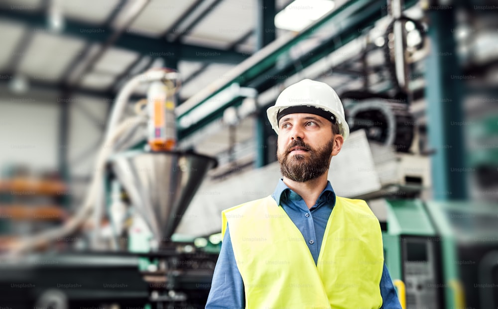 Ein Porträt eines glücklichen Industrieingenieurs, der in einer Fabrik steht. Speicherplatz kopieren.