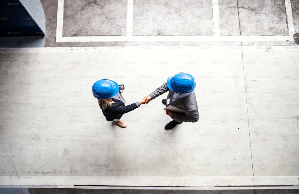 A top view of an industrial man and woman engineer in a factory, shaking hands. Copy space.