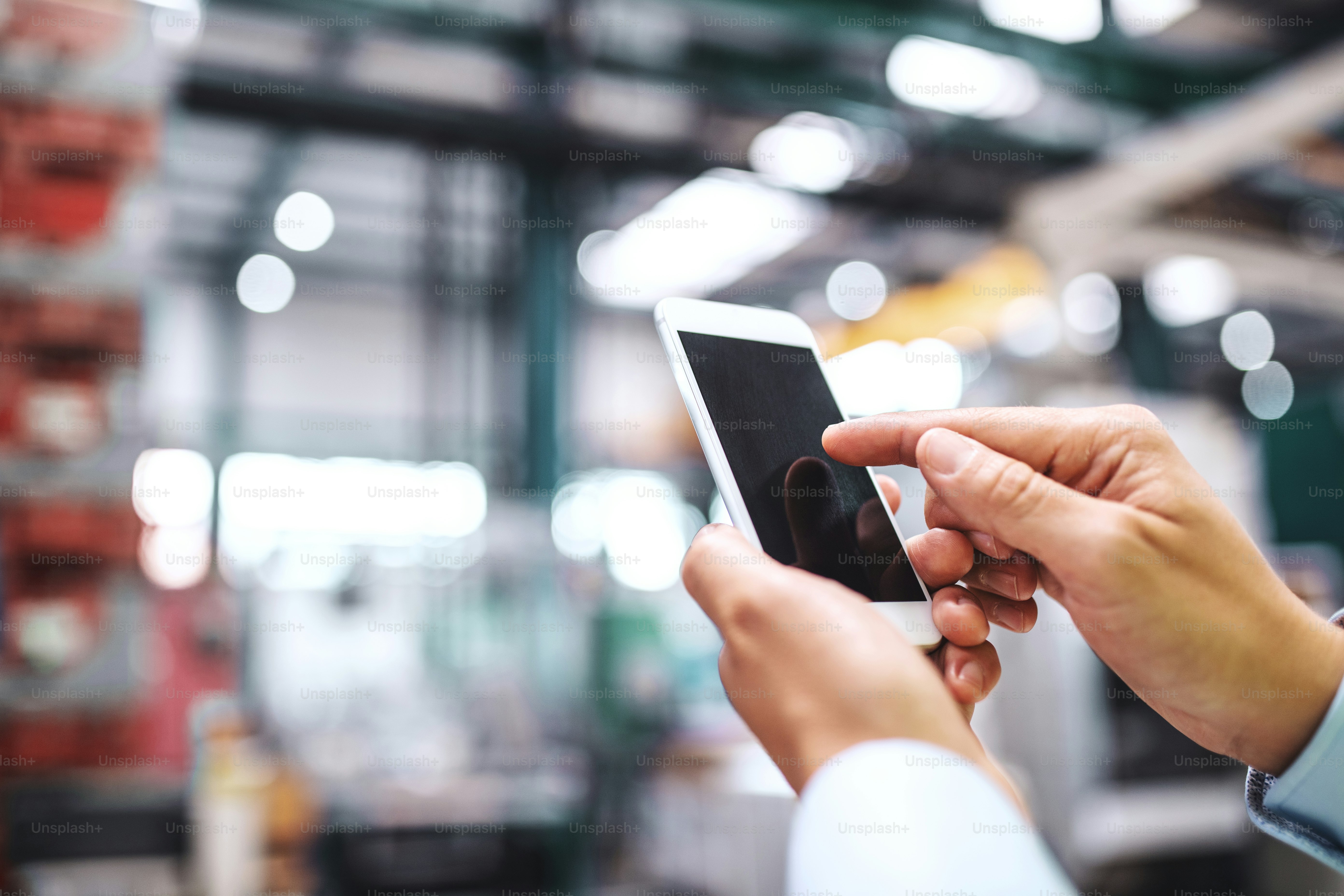Close-up of female hands in a factory using smartphone. Copy space.