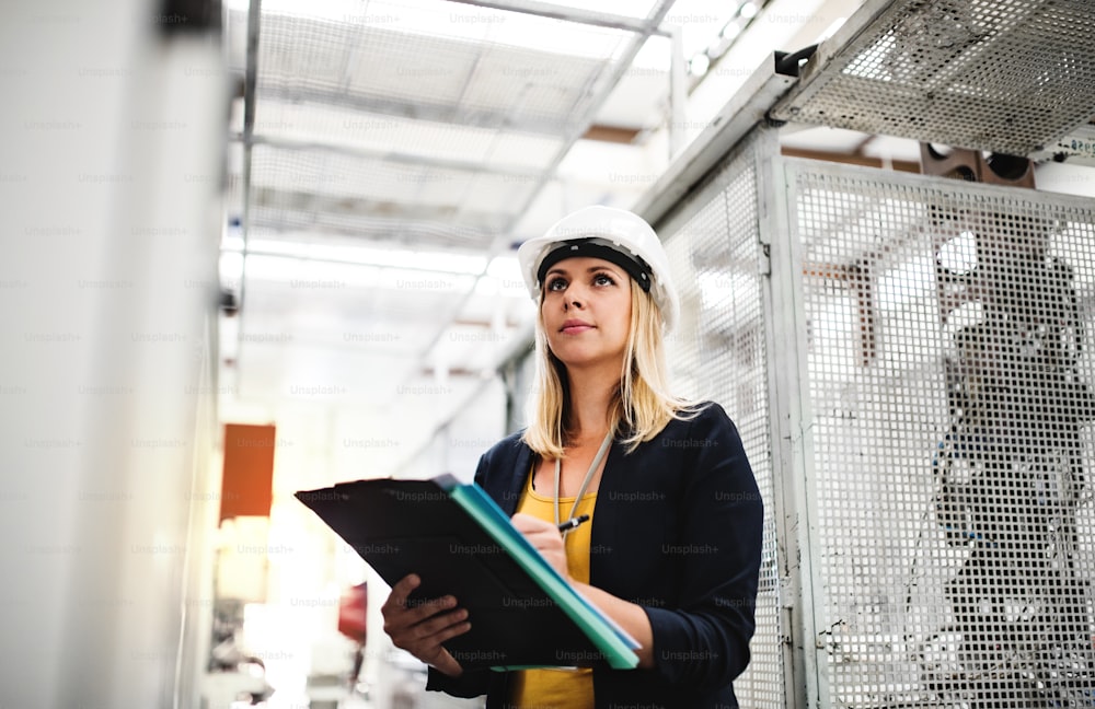 Um retrato de uma jovem engenheira industrial em uma fábrica verificando algo.