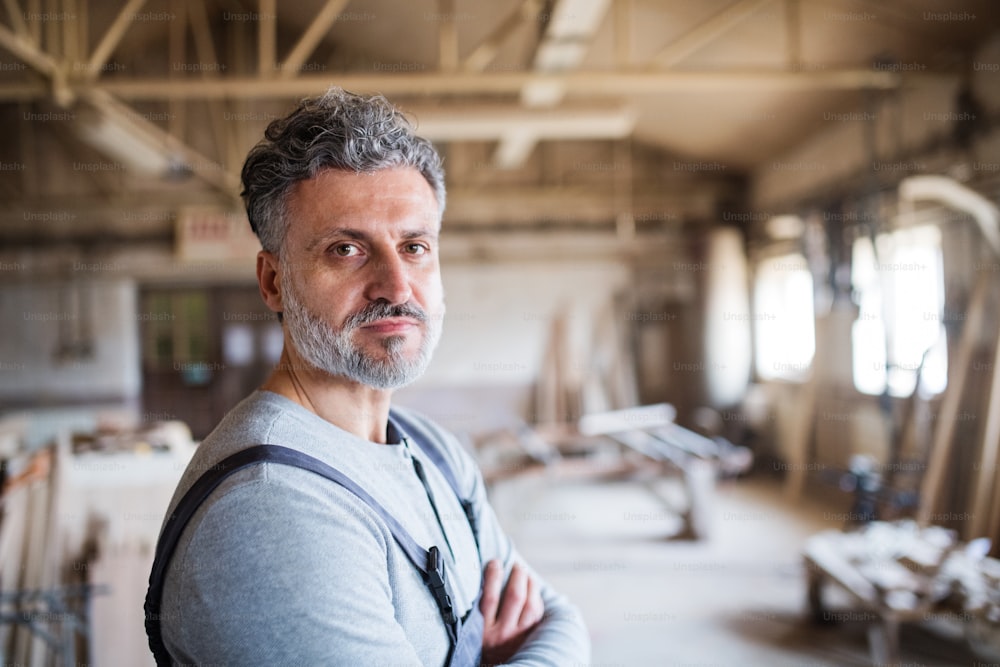 Portrait of a mature man worker in the carpentry workshop, arms crossed. Copy space.