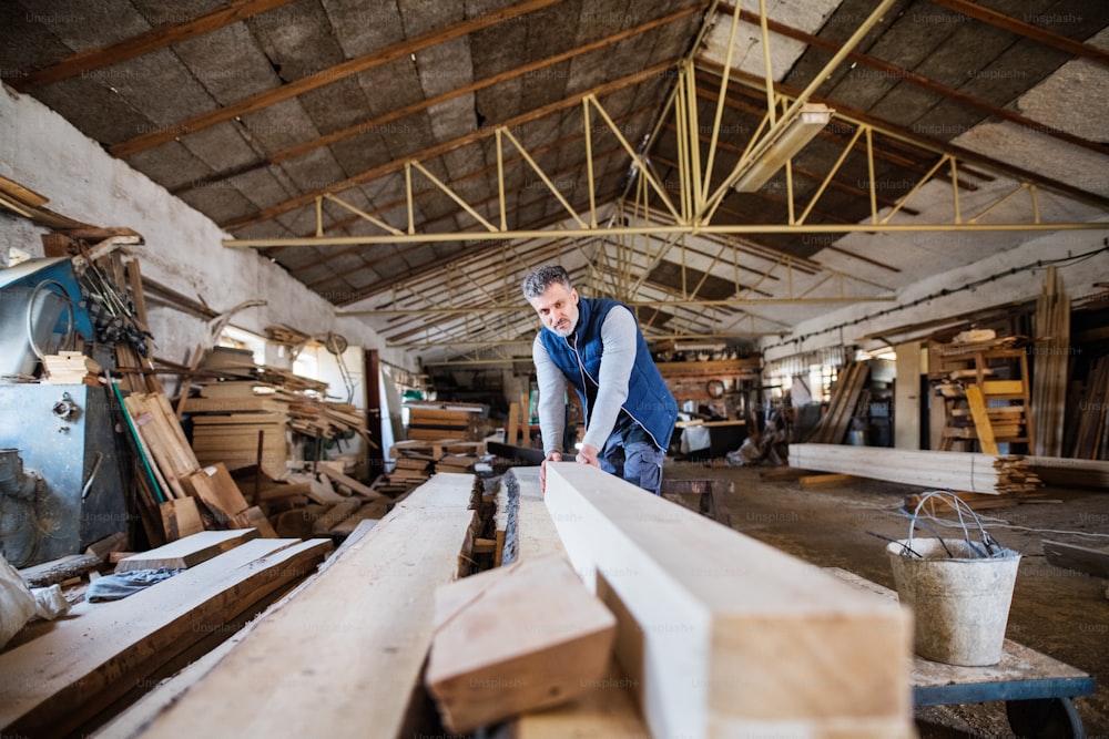 Un trabajador maduro en el taller de carpintería, trabajando con madera.