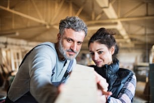 Portrait of a man and woman workers in the carpentry workshop, working together.