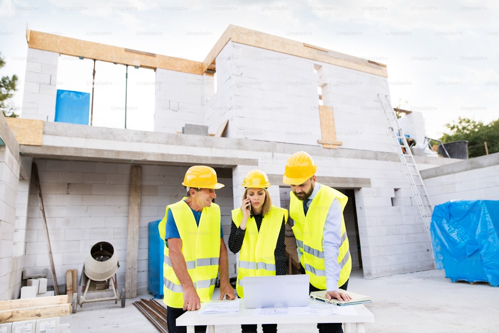 Architect, civil engineer and worker with a laptop and smartphone, discussing issues at the construction site.